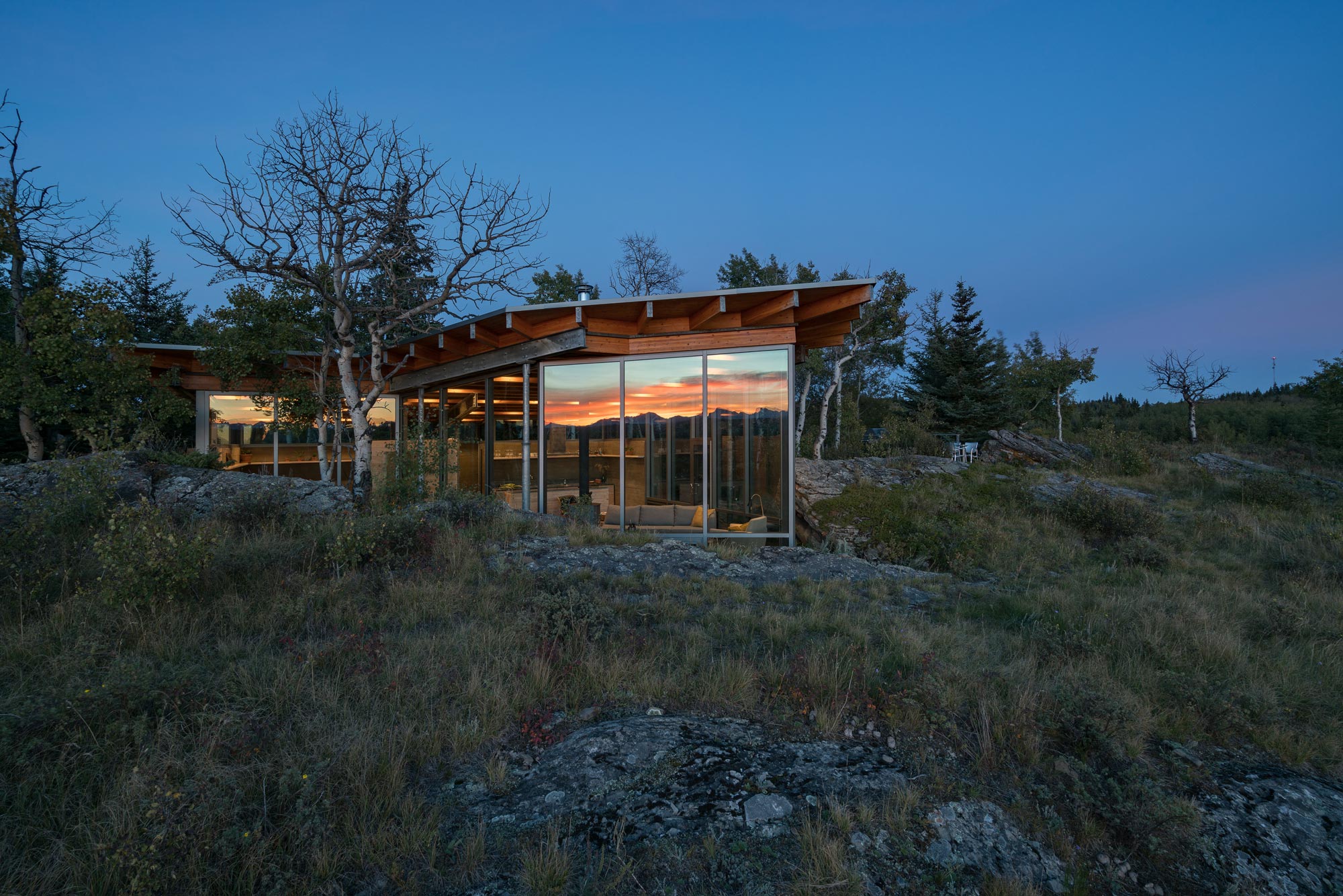 At dusk, the Rock House glazing reflects the Rocky Mountains.